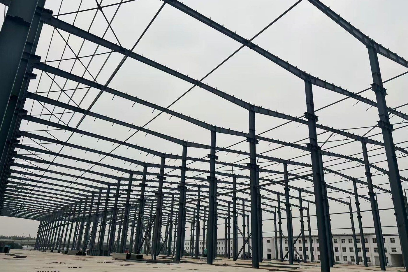 Erected steel portal frames running the length of a large building under construction on site in Brazil.